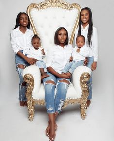 the family is posing for a photo in front of a white chair with gold trim