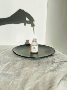 a person's hand holding a bottle on top of a tray next to a white wall