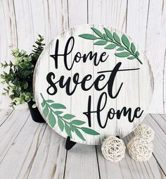 a wooden sign that says home sweet home next to some yarn balls and a potted plant