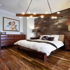 a bedroom with wood flooring and white bed in the center, along with two lamps on either side of the bed