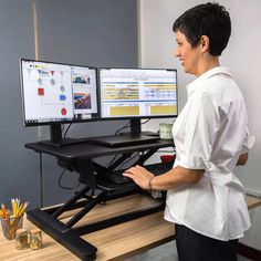 a woman standing in front of two computer monitors