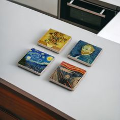 four coasters with paintings on them sitting on a counter