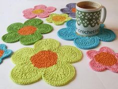 crocheted coasters with coffee cup and flower pattern on table top next to mug