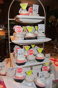 cupcakes are arranged on three tiered trays with street signs and traffic signs