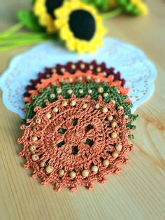 three crocheted doily sitting on top of a wooden table next to flowers