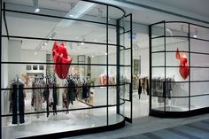 a clothing store with glass walls and mannequins in the window display area