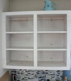 a white bookcase with glass doors on the top and bottom, in a kitchen