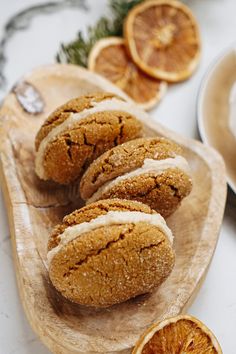 some oranges are sitting on a wooden platter with icing and cinnamon rolls