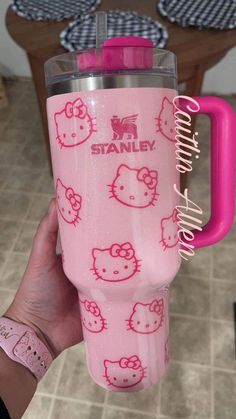 someone is holding a pink hello kitty travel mug with the word stanley on it and images of cats all over them