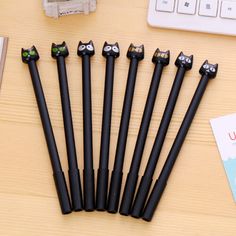 six black cats are sitting on top of the pen holders next to a computer keyboard