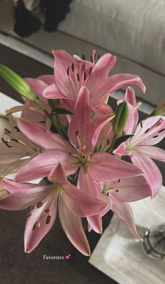 a bouquet of pink flowers in a vase on a table next to a white couch