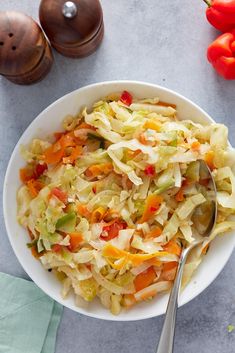 a white bowl filled with coleslaw next to red peppers