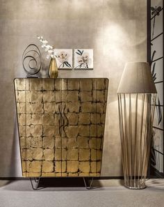 a gold sideboard with two vases on it and a lamp next to it