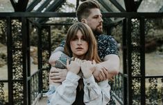 a man and woman standing next to each other with their arms wrapped around each other