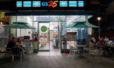 people sitting at tables in front of a store