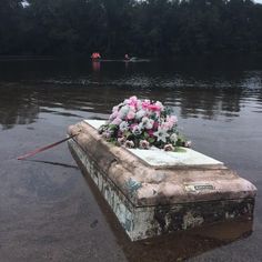 flowers are placed on top of an old concrete box in the middle of a body of water