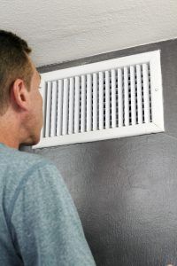 a man is looking at the air vent on the wall