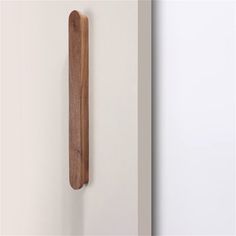 a wooden object hanging on the wall next to a white wall with a wood handle