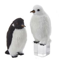 two stuffed penguins sitting on top of an ice block, one black and white the other gray