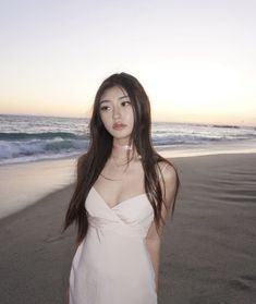 a woman standing on top of a beach next to the ocean