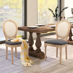 a dining room table with two chairs and a yellow blanket on the floor next to it