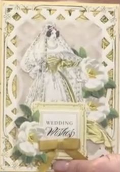 a hand holding up a wedding card with flowers on it