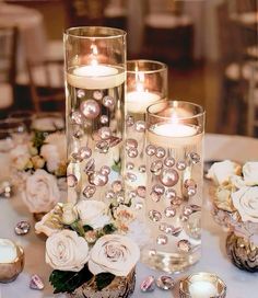 three tall candles are sitting on a table with flowers and other decorations around the candle holders