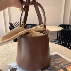 Expertly crafted from top-quality materials, this mini bag is unique and playful. A modern bucket bag, this piece comes in a rounded silhouette with bunny ear designs. You'll love the smooth look and feel of the luxurious leather, metal hardware, and youthful spirit of this leather accessory.Weight: 470 gHeight (cm): 17 Color: BrownStrap Length: 100-112 cmInterior Material: Flannel, PU leatherMaterial_bag: PU LeatherBagType: Handbag & Crossbody bagBag Length: 18 cm Brown Bucket Bag With Detachable Handle As Gift, Bucket Bag With Detachable Strap And Top Handle, Gift Bucket Bag With Detachable Strap And Top Handle, Beige Bucket Bag With Detachable Handle As Gift, Modern Bucket Shoulder Bag For Gift, Modern Bucket Bag For Gifts, Modern Bucket Bag For Gift, Modern Bucket Bag As Gift, Trendy Brown Bucket Bag With Top Handle