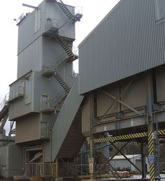 an industrial building with stairs going up to the top and below it, on a cloudy day