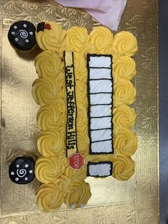 a cake shaped like a school bus on top of a gold tablecloth with black and white decorations