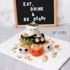 halloween sushi rolls are arranged on a white platter next to a sign that says eat, drink and be scary