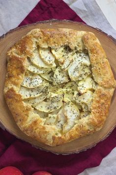 an apple pie on a wooden platter next to apples