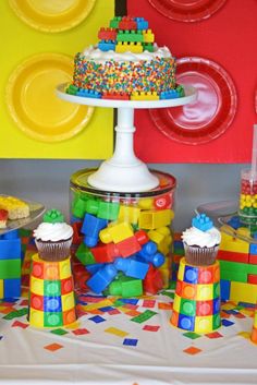 a table topped with cupcakes and cakes covered in lego blocks