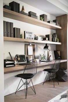 two chairs are sitting in front of the bookshelves on the wall next to each other