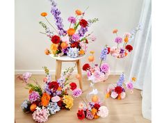 colorful flowers are arranged in vases on the floor next to a chair and table