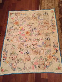 an old quilt is laying on the floor in front of a rug with birds and flowers