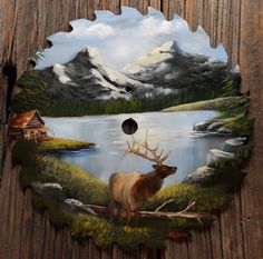 a clock with a painting of a deer on it's face and mountains in the background