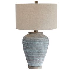 a blue and white lamp with a beige shade on the top, sitting in front of a white background