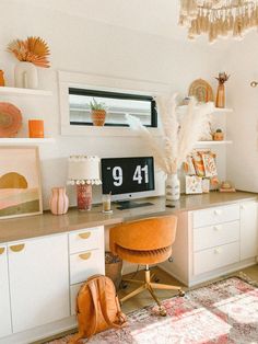 a desk with a chair, clock and other items on it in front of a window