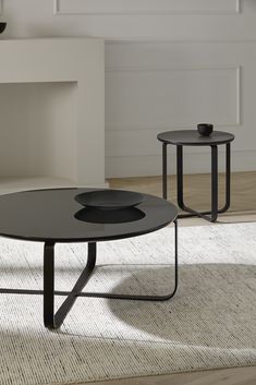 two black tables sitting on top of a rug in front of a fire place and fireplace