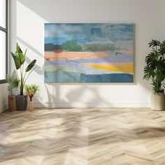 an empty room with wood flooring and large painting on the wall, along with potted plants