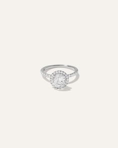 a white gold ring with diamonds on the band and an oval shaped diamond in the center