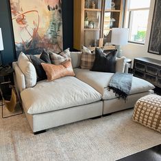 a living room filled with lots of furniture and pillows on top of a rug next to a window