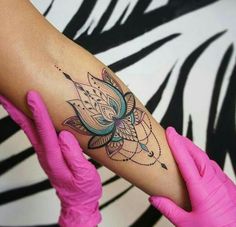 a woman's arm with a tattoo on it and pink gloves holding her hand