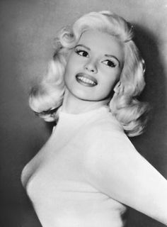 an old black and white photo of a woman with blonde hair wearing a high neck dress