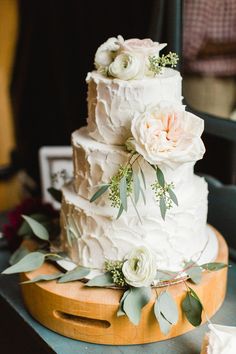 a white wedding cake with flowers and greenery