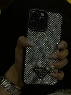 a woman holding up her phone case with diamonds on it