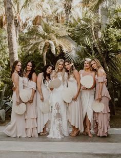 a group of women standing next to each other in front of palm trees and holding plates