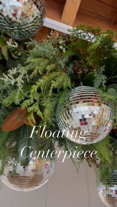 three mirrored disco balls hanging from the ceiling with ferns and other greenery around them