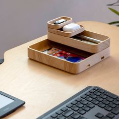 a wooden desk with a keyboard, mouse and cell phone on it next to a tablet